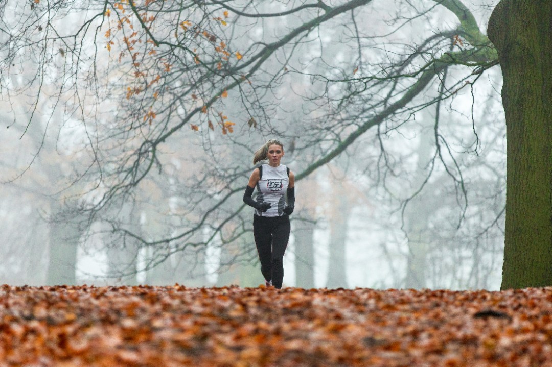 Woman running under bare tree in park