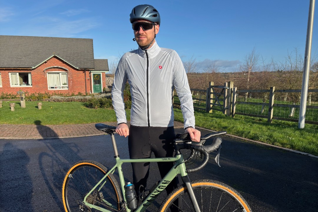 Male cyclist wearing Castelli Squall Shell jacket behind bike