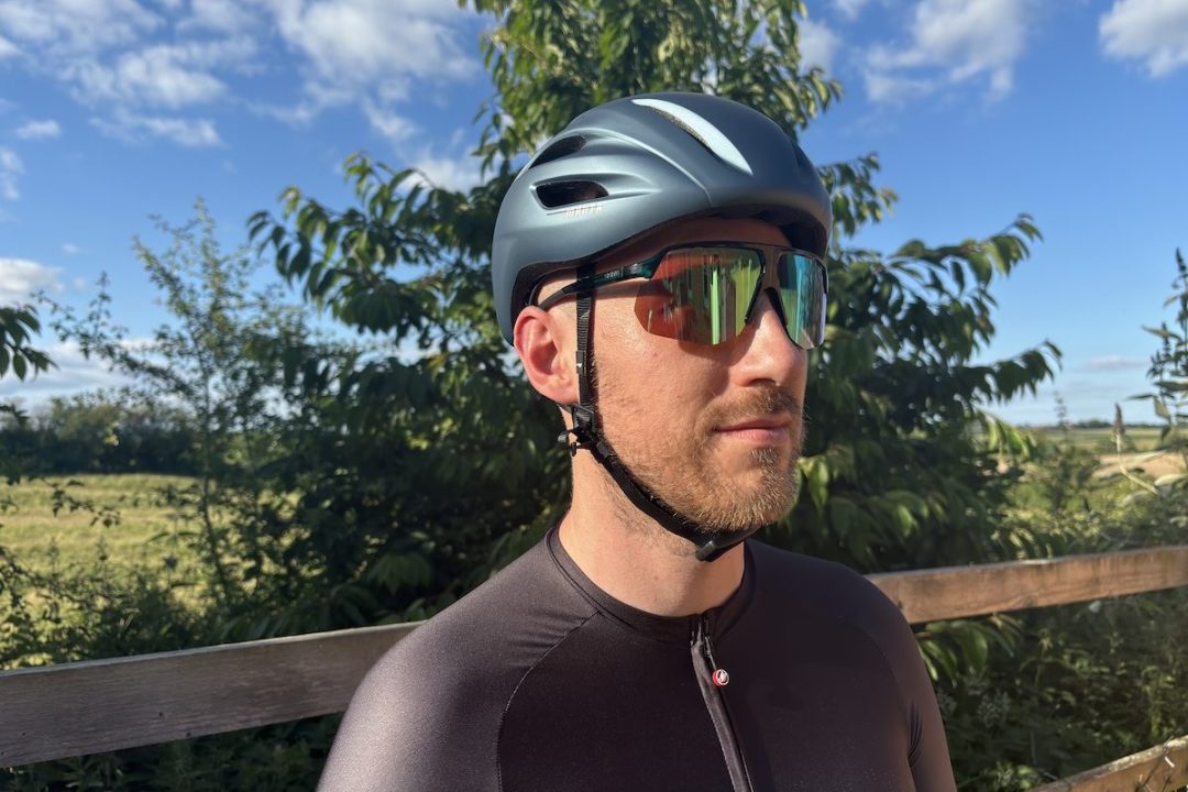 man wears sunglasses and bike helmet at an angle to the camera